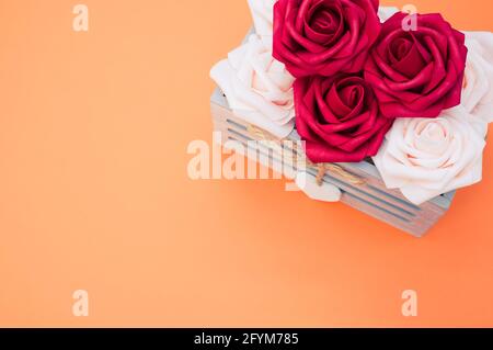 Rote und weiße Rosen in einer Box isoliert auf einem orangen Hintergrund Stockfoto