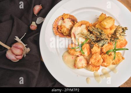 Peruanische Küche: Sautierte Garnelen mit Kräutern und Knoblauch, Holztisch, serviert auf einem weißen Teller, begleitet von purpurem Maissaft Stockfoto