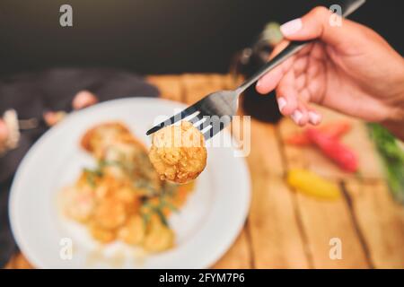 Peruanische Küche: Sautierte Garnelen mit Kräutern und Knoblauch, Holztisch, serviert auf einem weißen Teller, begleitet von purpurem Maissaft Stockfoto