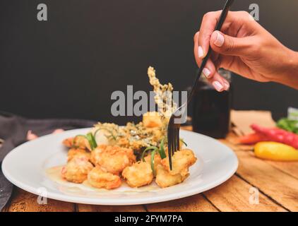 Peruanische Küche: Sautierte Garnelen mit Kräutern und Knoblauch, Holztisch, serviert auf einem weißen Teller, begleitet von purpurem Maissaft Stockfoto