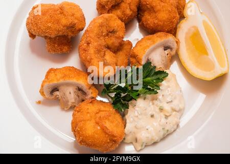 Panierte gebratene Champignons mit Tatarensauce und einem Zitronenkeil, in Wiener Stil gebackene Champignons oder Gebackene Schwammerl aus nächster Nähe Stockfoto