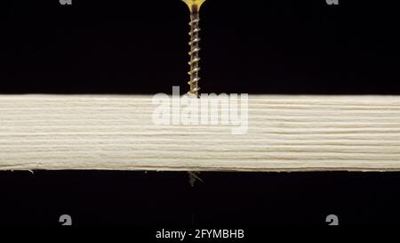 Foto eines Schraubendrehers, der die Gewindestift durch ein Holzbrett bohrt Stockfoto