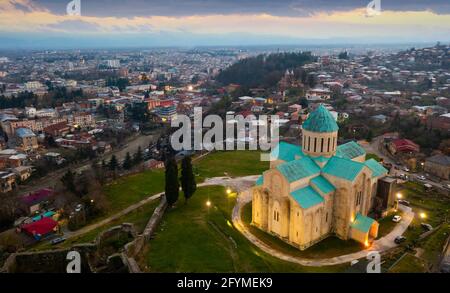 Blick von der Drohne auf beleuchteten wiederaufgebauten Gebäude der Kathedrale von Dormition, Tempel der georgisch-orthodoxen Kirche in Kutaisi gegen Stadtbild im Frühjahr e Stockfoto