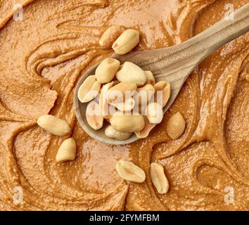 Löffel geröstete gesalzene Erdnüsse auf Erdnussbutter Hintergrund, Draufsicht Stockfoto