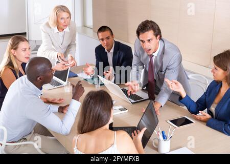 Internationale Gruppe von Geschäftspartnern, die bei der Besprechung im Büro emotional über Projekte und Ideen diskutieren Stockfoto