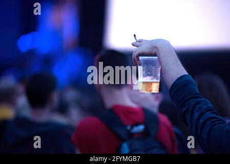 Hand in die Menge mit einer Plastikbox und einem Mit Bier und einer Zigarette bei einem Musikfestival Stockfoto