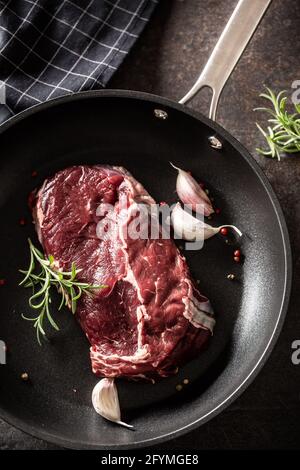 Frisches, rohes Rindfleisch Ribe Eye Steak in einer Teflonpfanne mit Rosmarin, Knoblauch, Salz und Pfeffer. Stockfoto