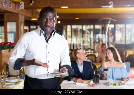 afroamerikanischer Kellner, der mit einem kleinen Trinkgeld im Restaurant Unmut ausdrückt Stockfoto