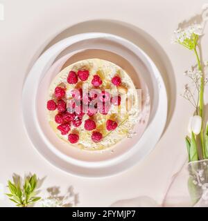 Hausgemachte Himbeere, Mandelkuchen auf einem weißen Teller auf einem rosa Hintergrund. Süßes Gebäck mit Mandelmehl ist glutenfrei, kohlenhydratarm. Keto-Diät Stockfoto