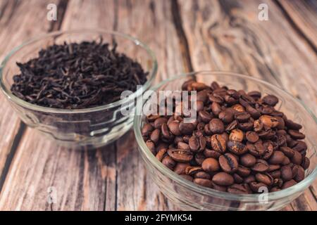 Geröstete Kaffeebohnen in einer Schüssel und gebrühter Tee im Hintergrund Stockfoto