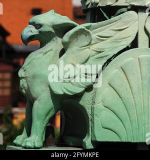 Einer der grünen Gripins oder Gryphons mit geschwungenen Adlerschnäbeln, die die Lampenstandards entlang der Balustraden der Drachenbrücke über den Fluss Ljubljanica in Ljubljana, Slowenien, unterstützen – Begleiter von vier furchterregend aussehenden und viel größeren grünen Kupferdrachen, die die vier Ecken der Struktur bewachen. Die Brücke wurde nach Entwürfen des dalmatinischen Architekten und Ingenieurs Jurij Zaninović (1876-1946) im Jugendstil / Wiener Secession erbaut und 1901, als Ljubljana eine Stadt im österreichisch-ungarischen Kaiserreich war, für den Verkehr geöffnet. Stockfoto