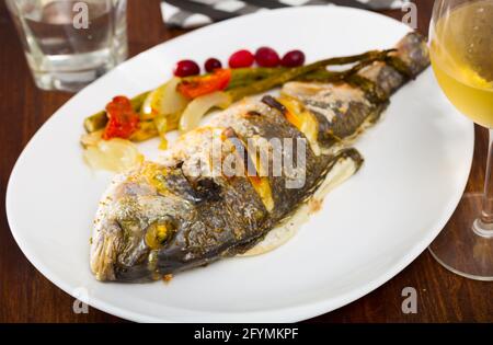 Dorade im Ofen gebacken serviert mit Spargel, Zwiebeln und Tomaten Stockfoto