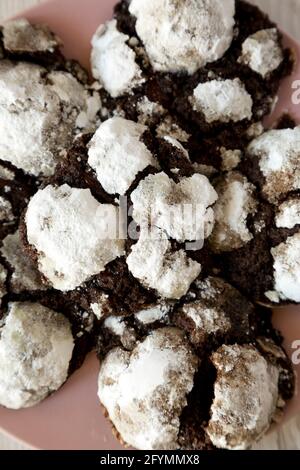 Hausgemachte Schokolade-Crinkle-Kekse auf einem rosa Teller auf einer weißen Holzoberfläche, Draufsicht. Flach liegend, über Kopf, von oben. Nahaufnahme. Stockfoto