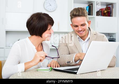 Reife Mutter und Sohn betrachten, neue Software auf dem Laptop am Tisch sitzen Stockfoto