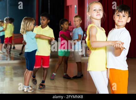 Lächelnde Kinder Grundschule versucht, Tanzen der Partner Tanz im modernen Studio Stockfoto