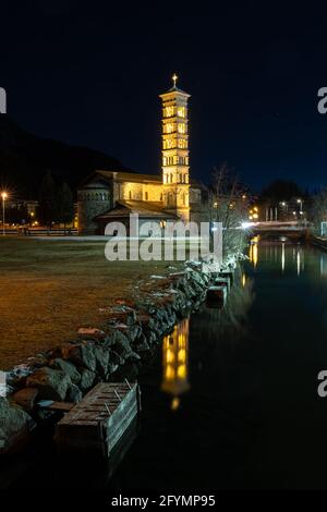 St. Moritz, Schweiz - 26. November 2020: Beleuchtete katholische Kirche St. Mauritius in der blauen Stunde und ihre Reflexion im See Stockfoto