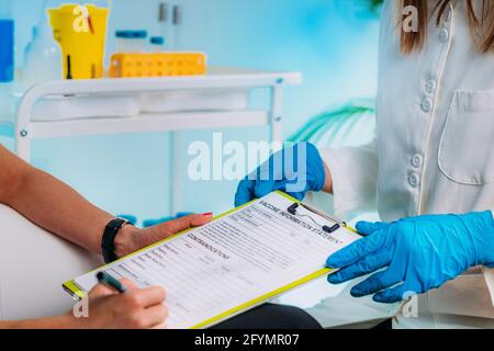 Weibliche Patientin, die eine Erklärung zur Impfstoffinformation ausfüllt Stockfoto
