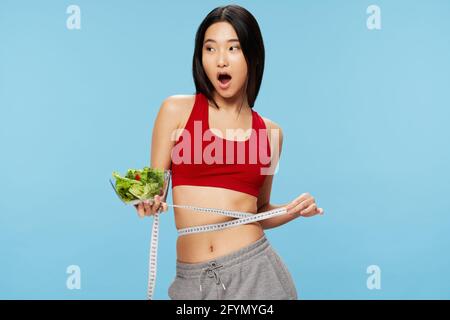 Schlanke Frau Essplatz mit Salat-Maßband Stockfoto