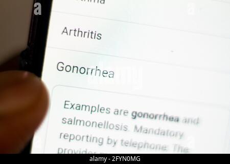 Gonorrhoe News.Nachrichten auf dem Handy.Handy in den Händen. Selektiver Fokus und chromatische Aberration Effekte. Stockfoto