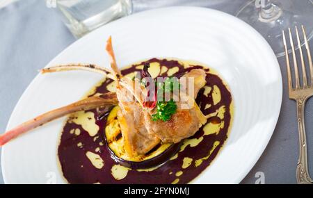 Köstliche gebackene Lamm Rippchen serviert auf weiße Platte mit gegrillten Auberginen, Rotweinsauce, Rosmarin und getrockneten Hibiscus Stockfoto