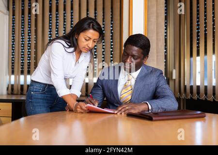 Geschäftsmann und Geschäftsfrau kommunizieren und unterzeichnen Dokumente am Verhandlungstisch im Büro Stockfoto
