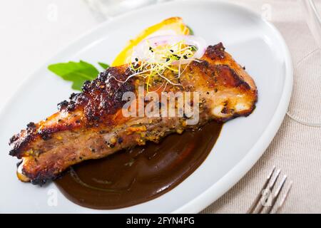 Geröstete würzige Schweineribs auf weißem Teller in Schokoladensauce mit gebackenen Kartoffeln und Gemüse serviert Stockfoto