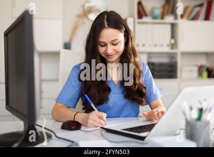 Porträt einer Ärztin, die mit einem Laptop arbeitet Stockfoto