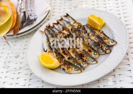 Eine Portion Sardinen vom Holzkohlegrill mit Zitrone, typische Meeresfrüchte-Vorspeise aus Malaga, Spanien Stockfoto