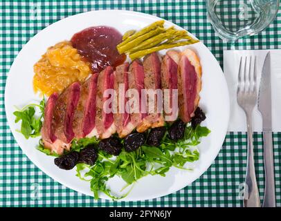 Leckere gegrillte Ente magret Filet mit grünen, Pflaumen, Spargel und Sauce serviert. Stockfoto