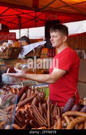 POZNAN, POLEN - 15. Aug 2013: Mann, der geräucherte Würstchen auf einem Lebensmittelmarkt verkauft Stockfoto