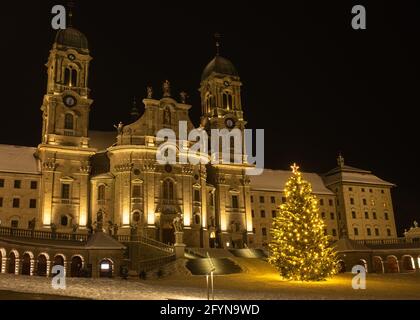 Die Benediktinerabtei Einsiedeln mit ihrer mächtigen Basilika ist das wichtigste katholische Wallfahrtszentrum der Schweiz. Weihnachtsbaum und verschneite Winter ni Stockfoto