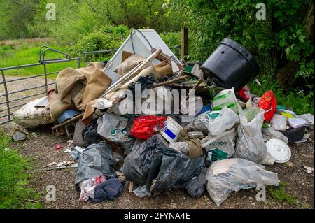 Coleshill, Buckinghamshire, Großbritannien. Mai 2021. Ein Landwirt konnte heute Morgen nicht auf sein Land zugreifen, da über Nacht ein großer Haufen Haushaltsmüll geflogen worden war, darunter Post von einer Adresse in der Streatham Road, London. Während der Pandemie von Covid-19 hat es in Buckinghamshire einen enormen Anstieg der illegalen Fliegenkippung gegeben, obwohl die Abfallentsorgungsstellen für den Handel geöffnet waren. Das Kippen von Fliegen ist eine Straftat, die mit einer Geldstrafe von bis zu £50,000 oder 12 Monaten Freiheitsstrafe vor einem Amtsgericht geahndet werden kann. Die Straftat kann eine unbegrenzte Geldstrafe und bis zu 5 Jahren Gefängnis anziehen, wenn sie in einem Crown Cou verurteilt wird Stockfoto