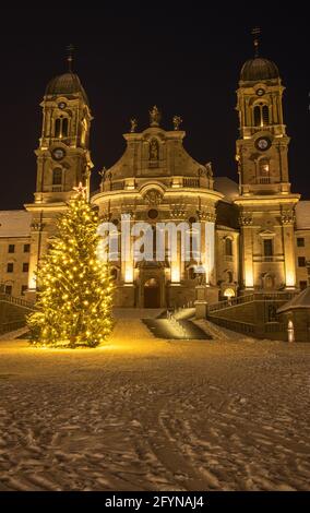 Die Benediktinerabtei Einsiedeln mit ihrer mächtigen Basilika ist das wichtigste katholische Wallfahrtszentrum der Schweiz. Weihnachtsbaum und verschneite Winter ni Stockfoto