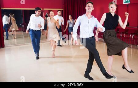 Junge lächelnde Menschen üben heftige jive Bewegungen im Tanz Klasse Stockfoto