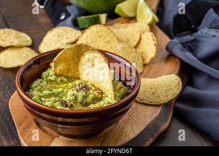 Schüssel mit Guacamole mit Tortilla-Chips auf Holzhintergrund Stockfoto