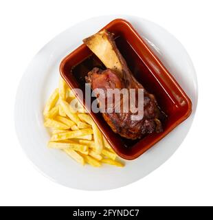 Nahaufnahme von köstlichem gebackenem Schweinshaxe mit pommes frites, serviert auf dem Teller. Isoliert auf weißem Hintergrund Stockfoto