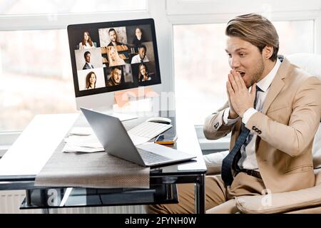 Aufgeregt kaukasischen Mann hält seine Hände in der Nähe Gesicht überrascht, sitzen am Schreibtisch im Büro, fühlen sich mit Arbeitsnachrichten, überglücklich männlich Post am Laptop Stockfoto