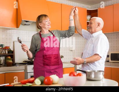 Fröhliche liebende ältere Paare tanzen in gemütlicher Hausküche Stockfoto