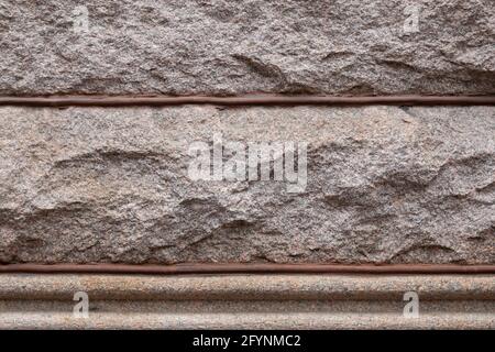 Hintergrund von rustikalen Granitblöcken durch Perlenmörtel geteilt, architektonische Details, horizontaler Aspekt Stockfoto