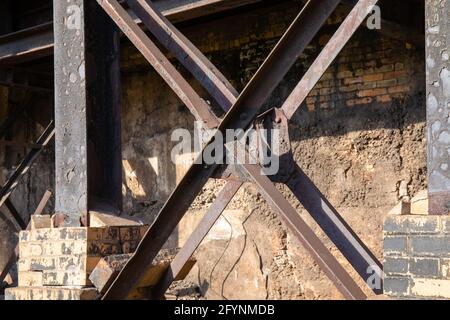 Verrostete Metallträger vor einer alten Ziegelmauer, Sonnenschein und Schatten, horizontaler Aspekt Stockfoto
