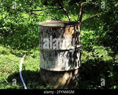 Im Sommer steht im Garten ein Metallwasserfass Stockfoto