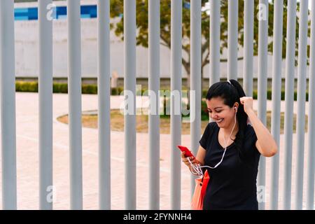 Sportliche Frau, die in einem Park steht und ihr Handy überprüft Stockfoto