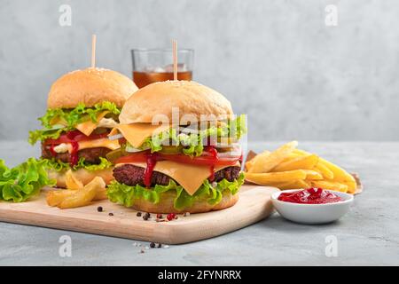 Leckere hausgemachte Burger, Pommes Frites und Cola auf grauem Hintergrund mit Platz zum Kopieren. Fast Food. Stockfoto