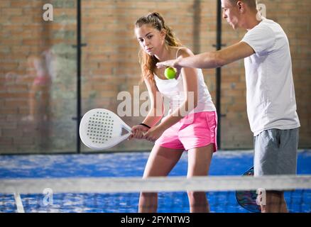 Der Trainer lehrt eine Frau, Padel auf dem Tennisplatz zu spielen Stockfoto