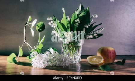 Stillleben mit einem Zweig aus weißem Flieder und Lilien Des Tals in einem Glaskrug Stockfoto