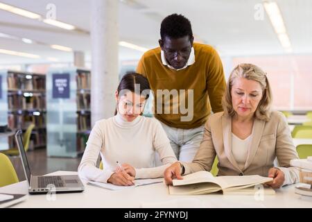 Tutorin hilft Studenten, die sich auf die Prüfung in der Bibliothek vorbereiten Stockfoto