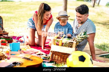 Glückliche Familie, die gemeinsam Spaß auf Picknick-Party hat - Lebensstilkonzept Freude und Liebe mit Mutter und Vater, die mit Kind im Park spielen Stockfoto