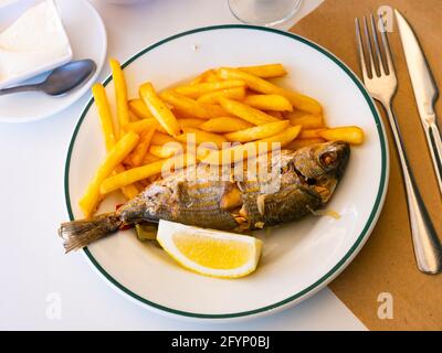 Gebratener Sarpa-Salpa-Fisch mit Kartoffeln und Zitrone aus nächster Nähe auf einem Teller Stockfoto