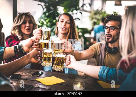 Freunde toasten Bier in der Brauereibar drinnen auf der Dachparty - Freundschaftskonzept mit jungen Leuten, die Spaß haben, zusammen zu trinken zur Happy Hour Stockfoto