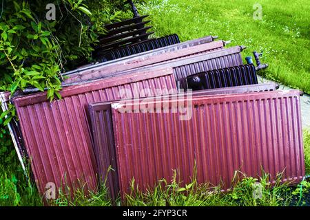 Alte Heizkörper im grünen Hof. Austausch gebrauchter Heizkörper im Haus. Altmetallsammlung für das Recycling vorbereitet. Stockfoto